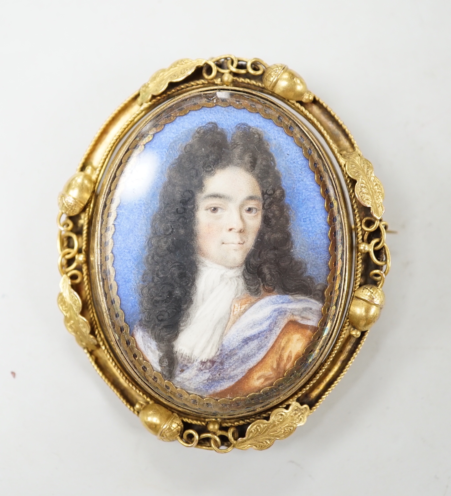 A Georgian yellow metal mounted oval portrait watercolour of a gentleman, with acorn and leaf border, 58mm.